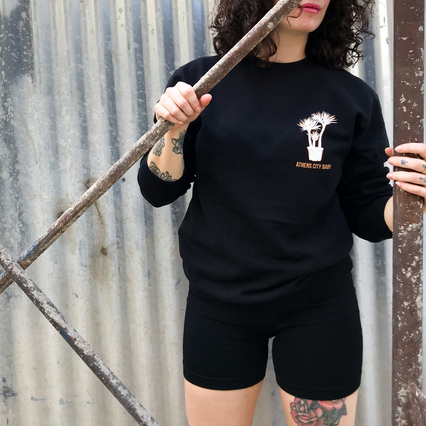 lady in front of a construction site (door) wearing the sweatshirt with the front design visible
