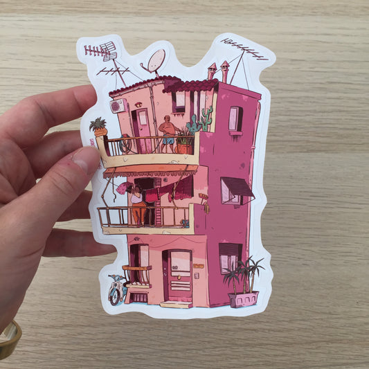 The sticker is hold by a hand above a table wooden.