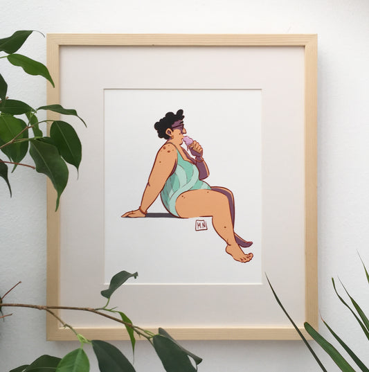 Framed art work of a lady eating an ice cream in her bathing suit.